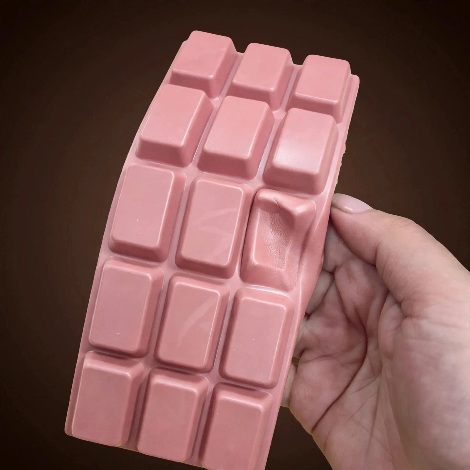 Hand squeezing the pink chocolate tablet squishy