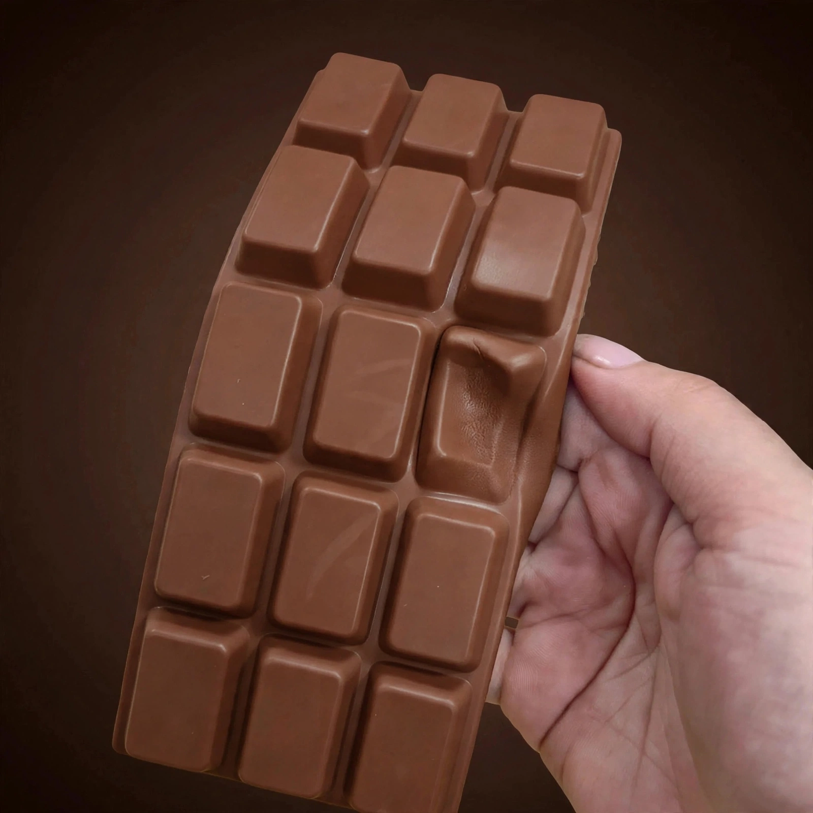 Hand squeezing the brown chocolate tablet squishy
