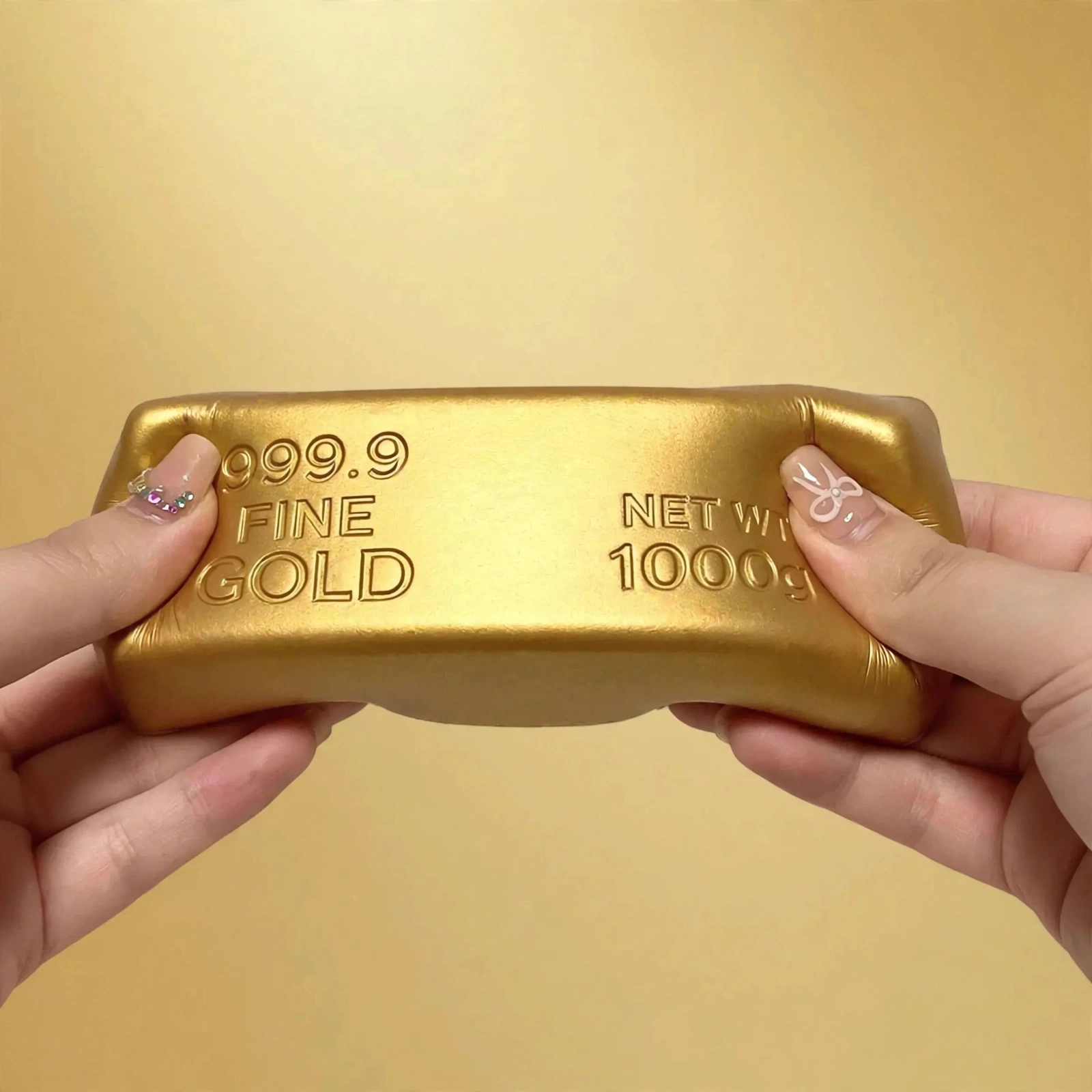 Hands squeezing the soft gold brick squishy foam bar