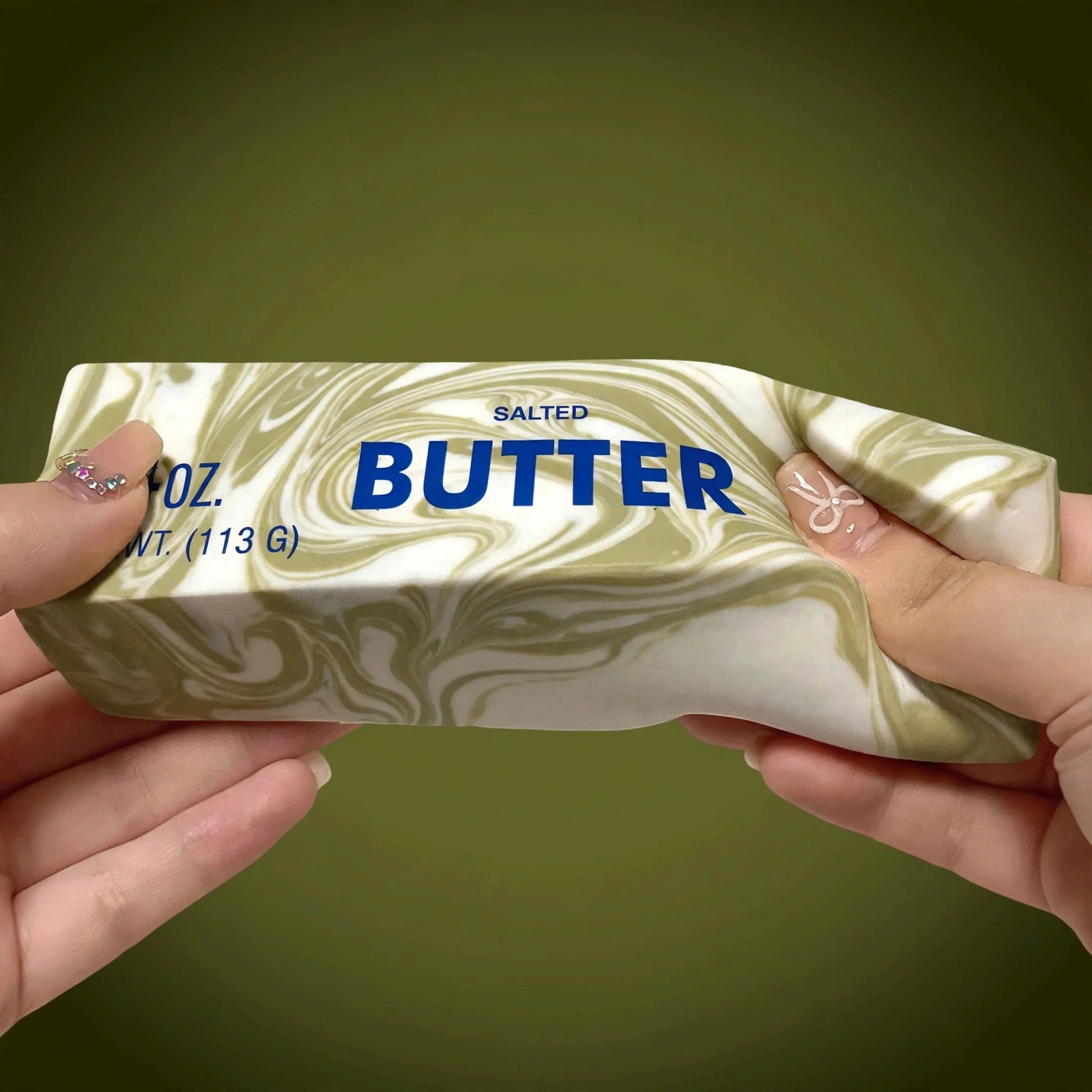 Hands squeezing the Green marble butter squishy 4oz soft foam
