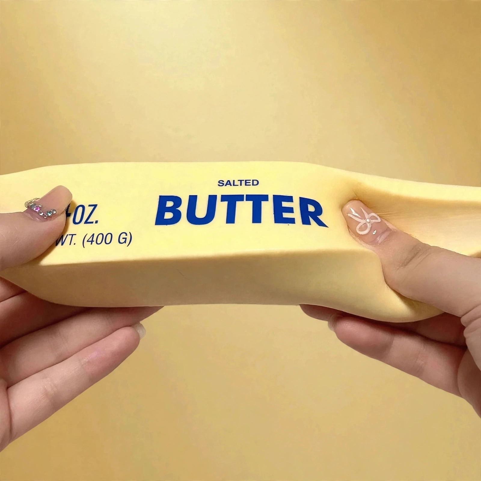 Hands bending the jumbo 14oz butter squishy to show its soft slow-rise foam