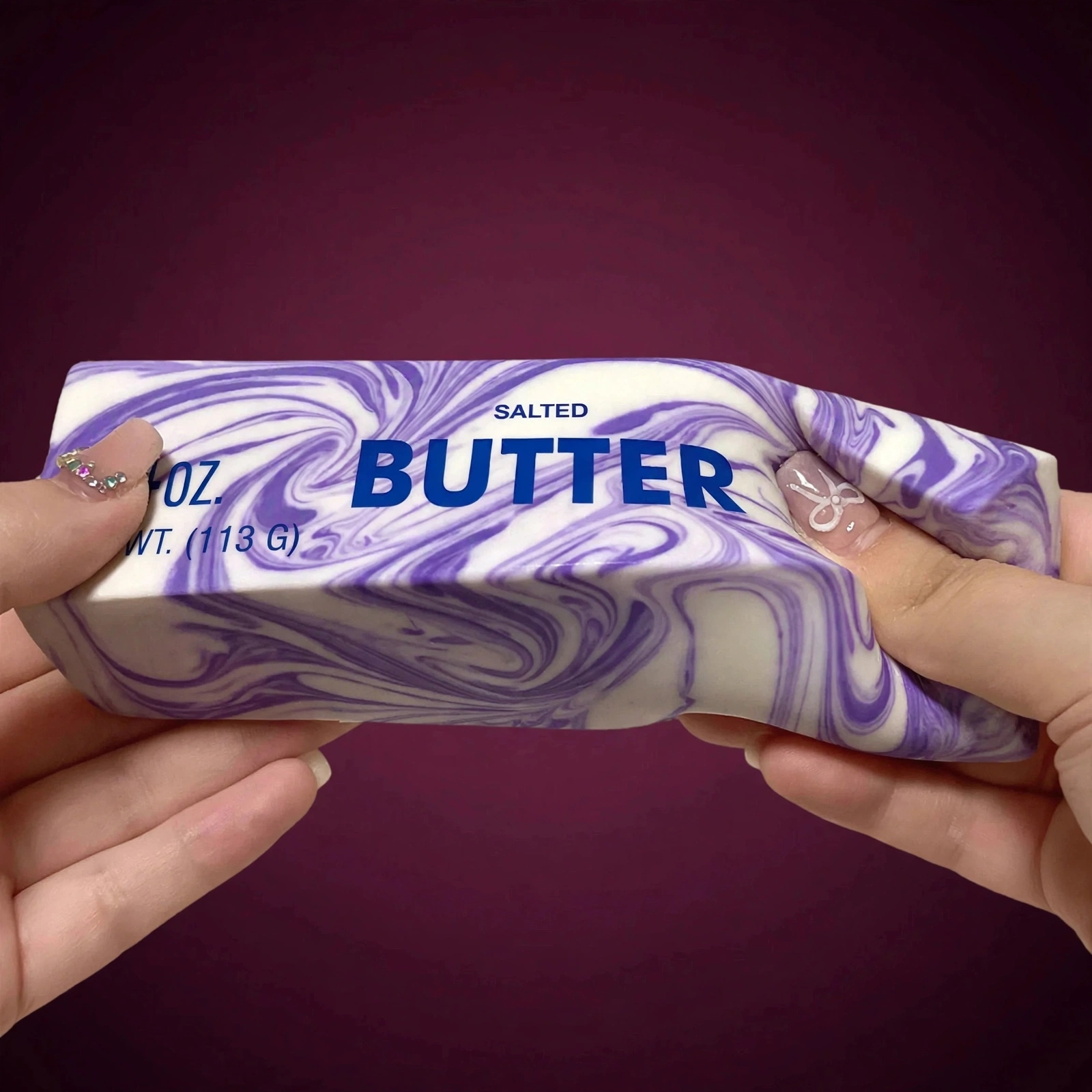 Hands squeezing the Purple marble butter squishy 4oz soft foam